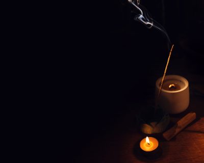 Incense aroma sticks smoldering on table lotus holder and candle in darkness. Zen, meditation, mental health comfort zone.