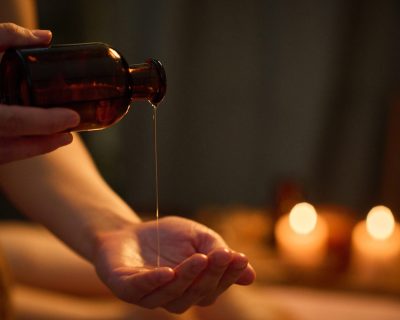Medium close up of unrecognizable female hand holding jar and pouring essential oil into palm